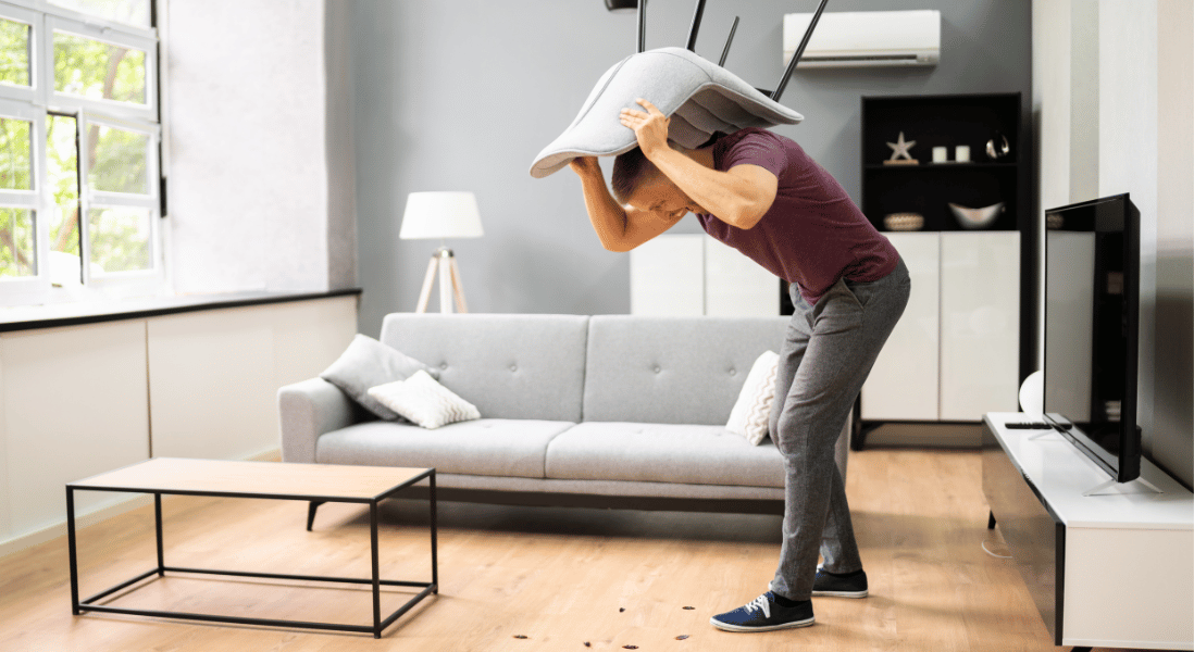 guy frustrated in the dinning room , trying to hit the cockroaches with the chair