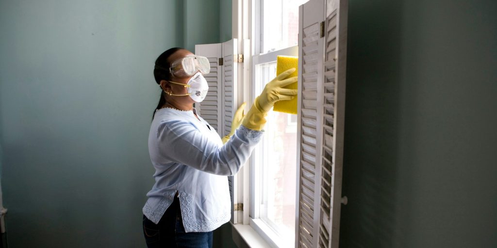 woman in white long sleeve shirt and blue denim jeans standing beside white wooden framed glass